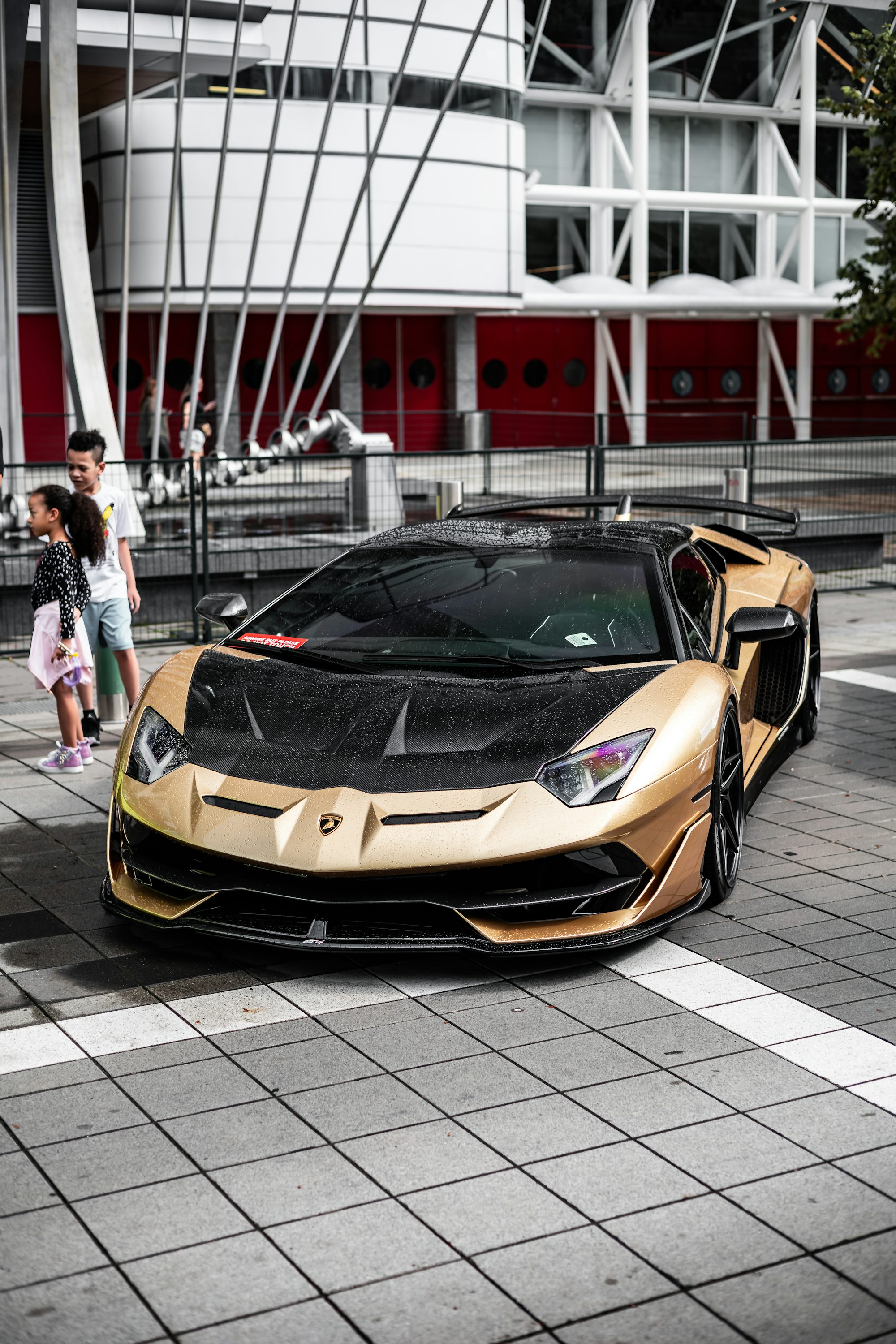 a gold and black sports car parked in front of a building